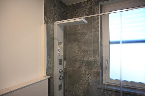 een douche met een glazen deur naast een raam bij La Finestra Blu Alba 2 in Alba
