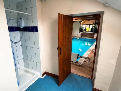 La salle de bains est pourvue d'une douche et d'une porte menant à une piscine. dans l'établissement Fern Cottage, Triscombe Farm Cottages, à Wheddon Cross
