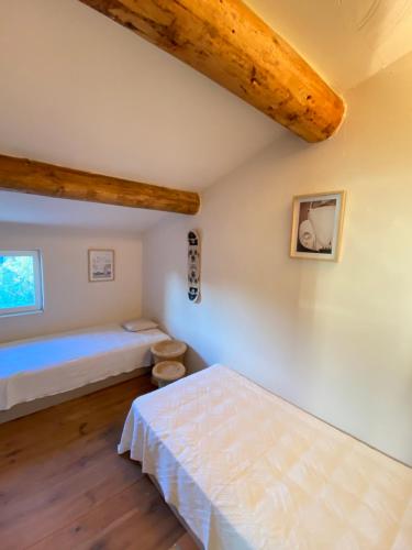 une chambre avec deux lits et un plafond en bois dans l'établissement Authentique Mazet et sa fontaine en Provence, à Fontvieille