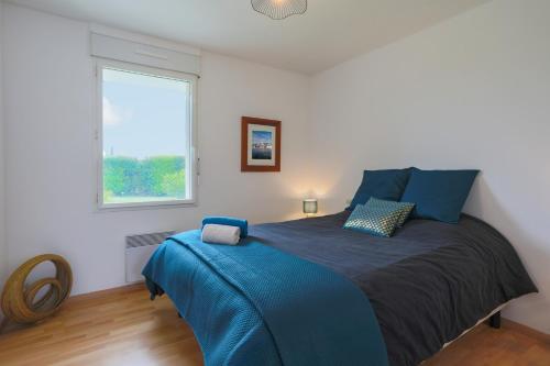 Schlafzimmer mit einem Bett mit blauer Bettwäsche und einem Fenster in der Unterkunft La Dolce Vita in Langoat