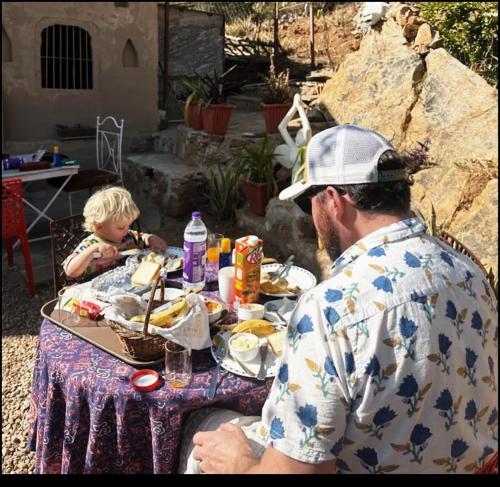un hombre y un niño sentados en una mesa comiendo comida en Raj Haveli- A Heritage Samode en Jaipur
