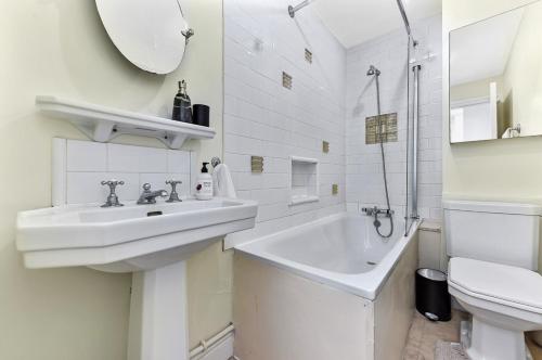 ein weißes Bad mit einem Waschbecken und einem WC in der Unterkunft Royal Kensington 1 Bedroom Apartment in London