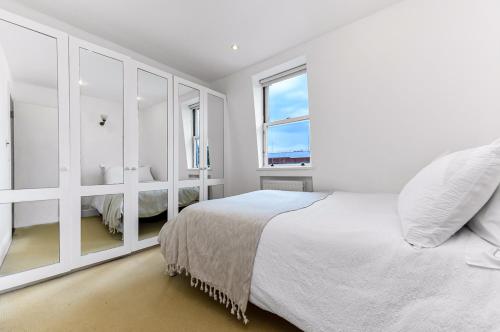 ein weißes Schlafzimmer mit einem großen Bett und einem Fenster in der Unterkunft Royal Kensington 1 Bedroom Apartment in London