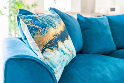 a blue couch with a blue and gold pillow on it at New 2 Bedroom Deluxe Apartment - Parking - Wifi & Netflix - Top Rated - 50C in Sleightholme
