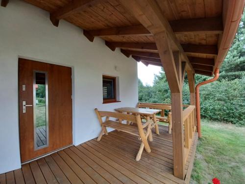 porche de madera con mesa y banco en la cubierta en Domek, domki na Mazurach. Okolice Olecka, en Swiętajno