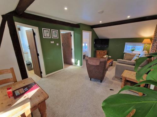 a living room with green walls and a couch at The Hayloft in Ivinghoe