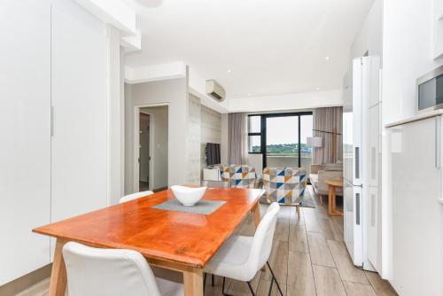 a kitchen and dining room with a wooden table and chairs at The Regency Apartments in Pretoria