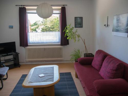 uma sala de estar com um sofá vermelho e uma mesa em 080 Ferienwohnungen Neuengroden em Wilhelmshaven