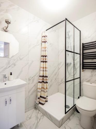 a white bathroom with a shower and a toilet at WAW Pokoje Ursynów in Warsaw