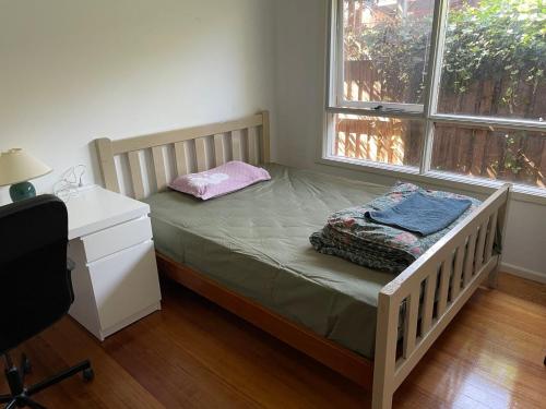 a bed in a room with a desk and a window at E电车公交商圈大学附近别墅大床间Neighbors of chain supermarkets in Melbourne