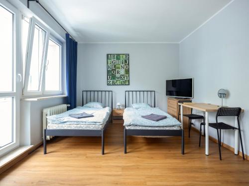1 Schlafzimmer mit 2 Betten, einem Schreibtisch und einem Tisch in der Unterkunft WAW Pokoje Ursynów in Warschau