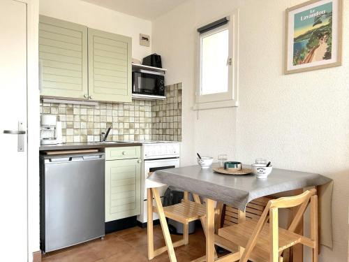 une cuisine avec une table et quelques chaises dans l'établissement Studio calme avec coin nuit, terrasse et parking - Proche plage et commerces - FR-1-251-420, au Lavandou