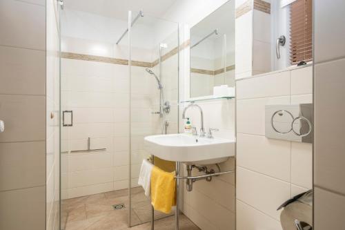 a bathroom with a sink and a shower at Hotel-Pension Falkensteiner in Sankt Gilgen