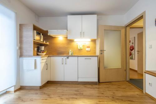 a kitchen with white cabinets and a wooden floor at Hotel-Pension Falkensteiner in Sankt Gilgen
