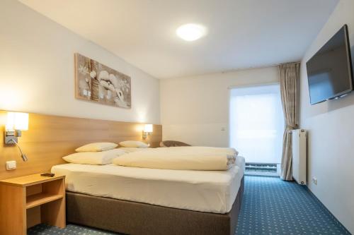 a hotel room with two beds and a flat screen tv at Hotel-Pension Falkensteiner in Sankt Gilgen