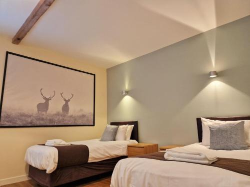 two beds in a room with two deer paintings on the wall at Ridgeway in Leighton Buzzard