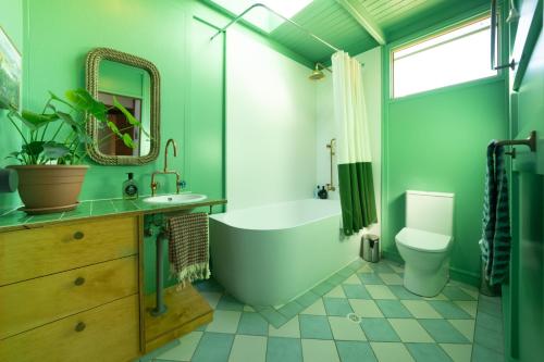 a green bathroom with a tub and a toilet at Porpoise Palace, The South Coast Sandcastles in Huskisson in Huskisson