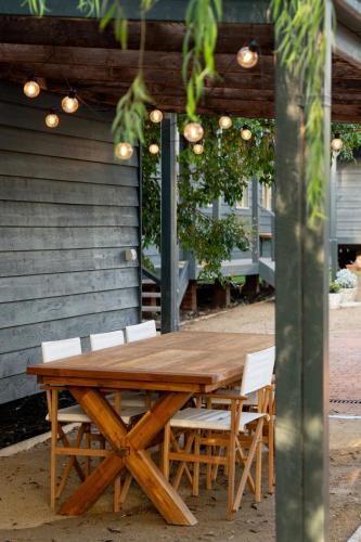 a wooden table with white chairs and a wooden ceiling at Shell House The South Coast Sandcastles in Huskisson in Huskisson