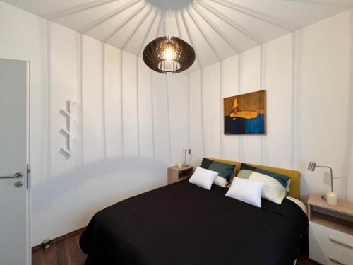 um quarto com uma cama preta e almofadas brancas em Bonvenon em Szombathely