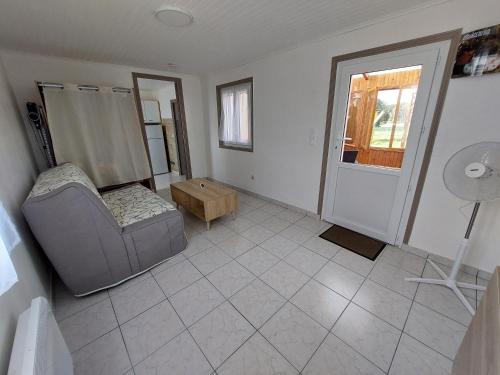 un soggiorno con una sedia e un tavolo di La Petite Maison à la Campagne a Guer