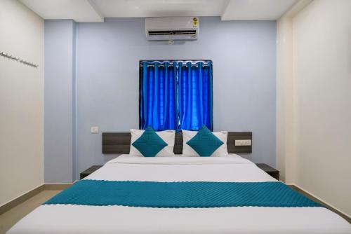 a bedroom with a large bed with blue curtains at The Balcony Suites in Hyderabad