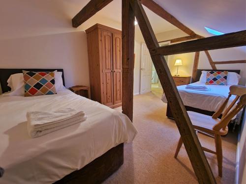 a bedroom with two beds and a chair in a room at Barnyard Cottage in Leighton Buzzard