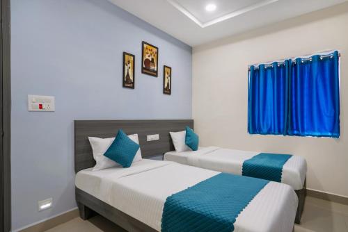 two beds in a room with blue curtains at The Balcony Suites in Hyderabad