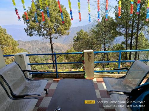 a table and chairs on a balcony with a view at Joshi Holiday Home Stay in Lansdowne