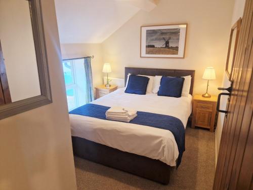 a bedroom with a large bed with blue pillows at The Granary in Leighton Buzzard