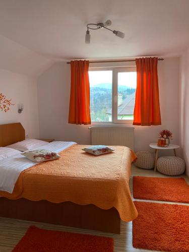 Schlafzimmer mit einem Bett und einem Fenster mit orangefarbenen Vorhängen in der Unterkunft Casa Nicole in Moieciu de Jos