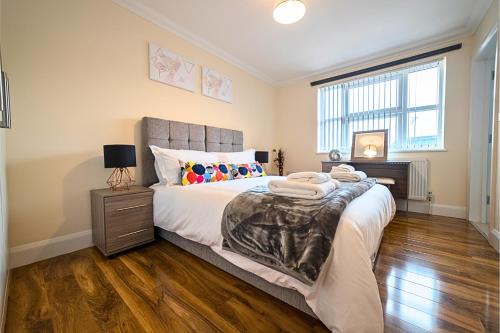 um quarto com uma cama grande e piso em madeira em Heathrow RARE find 2 Bedroom plus 2 Bathroom flat - Sleeps 6- Free Parking- Close to Heathrow Terminals-Quiet development em Stanwell