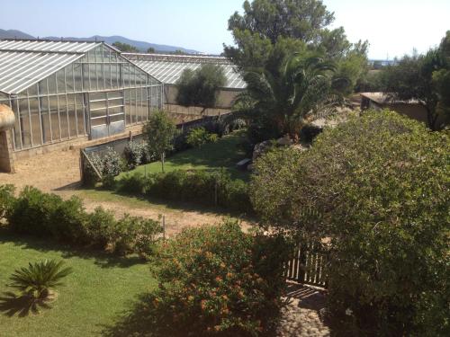 a garden with a greenhouse and trees and bushes at La Contea in SantʼAnna Arresi