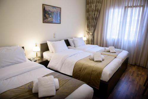 a hotel room with three beds with towels on them at Hotel Padelidaki in Tríkala
