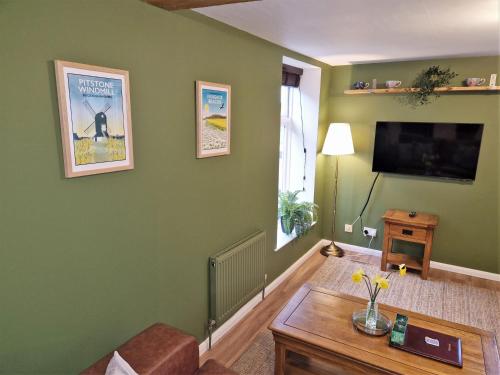 a living room with green walls and a flat screen tv at The Mill in Leighton Buzzard