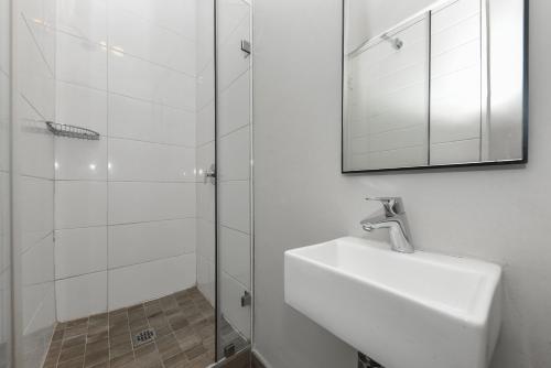 a bathroom with a sink and a shower with a mirror at The Regency Apartments in Pretoria