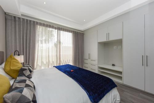 a bedroom with a bed and a large window at The Regency Apartments in Pretoria