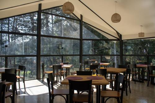 a restaurant with tables and chairs and large windows at Pousada Hogareña in Campos do Jordão