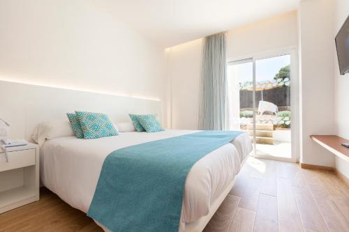 a bedroom with a bed and a large window at Mar Hotels Playa Mar & Spa in Port de Pollensa