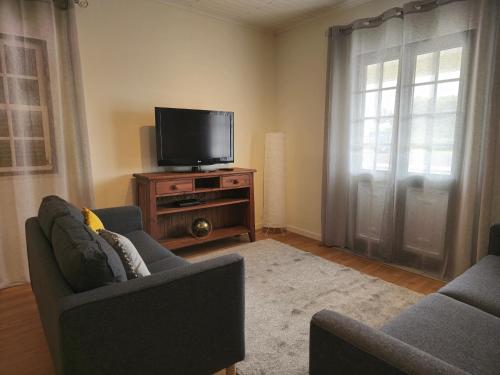 a living room with two chairs and a flat screen tv at Casa da Villa in Madalena