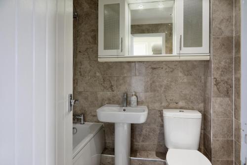 Cosy tastefully decorated flat in Rainham في رينهام: حمام مع حوض ومرحاض ومرآة