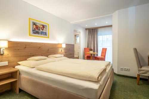 a hotel room with a large bed and a desk at Hotel-Pension Falkensteiner in Sankt Gilgen