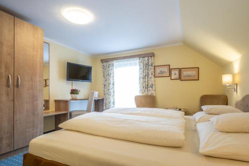 a hotel room with two beds and a television at Hotel-Pension Falkensteiner in Sankt Gilgen