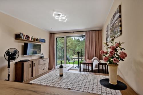 a living room with a table with a vase of flowers at Apartament Orlando w Porto Łeba 350m od morza in Łeba