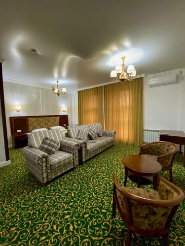 uma sala de estar com um sofá, uma mesa e cadeiras em Гостиничный комплекс Белес em Zaozërnyy