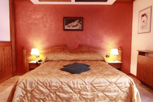 a bedroom with a bed with a blue shirt on it at G. Hotel Des Alpes (Classic since 1912) in San Martino di Castrozza