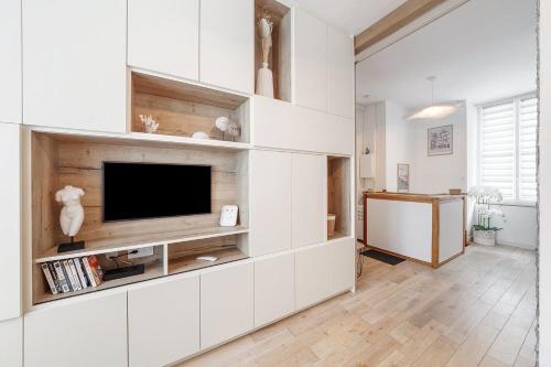 een woonkamer met witte kasten en een flatscreen-tv bij Tassigny - Charmant appartement/ terrasse - Port in Vannes