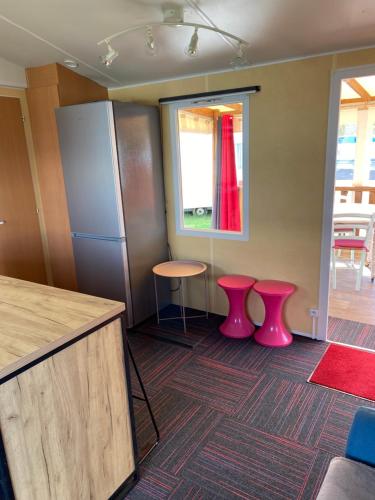 a kitchen with pink stools and a counter and a window at Mobil Home 5 personnes - Camping *** Les Ollivaud- in La Baule