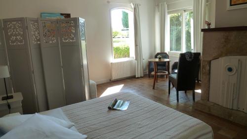een slaapkamer met een bed, een stoel en een tafel bij Chambres d'hôtes Le Saleix in Donzenac