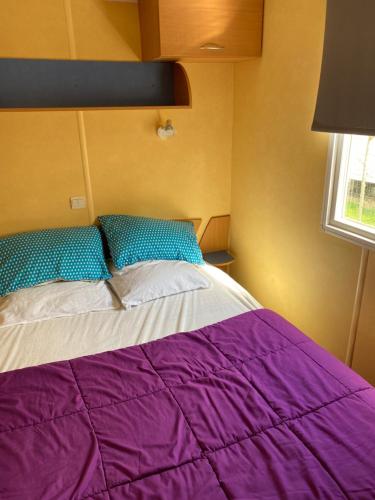 a bedroom with a purple bed with a window at Mobil Home 5 personnes - Camping *** Les Ollivaud- in La Baule