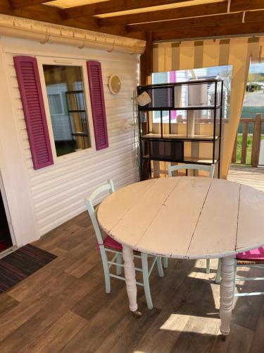 - une table et des chaises sur la terrasse couverte d'une maison dans l'établissement Mobil Home 5 personnes - Camping *** Les Ollivaud-, à La Baule